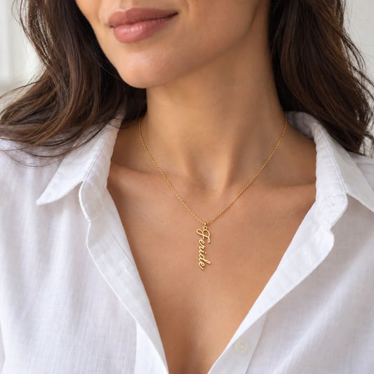CHOICE Florisse Dikey Çiçek Detaylı İsim Kolye, Feride kişiselleştirme örneği; 925 ayar gümüş üzerine 14 ayar altın kaplama; beyaz gömlekli kadın modelde minimal duruş